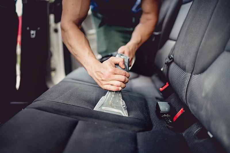 A service mechanic vaccuming the seats in a car